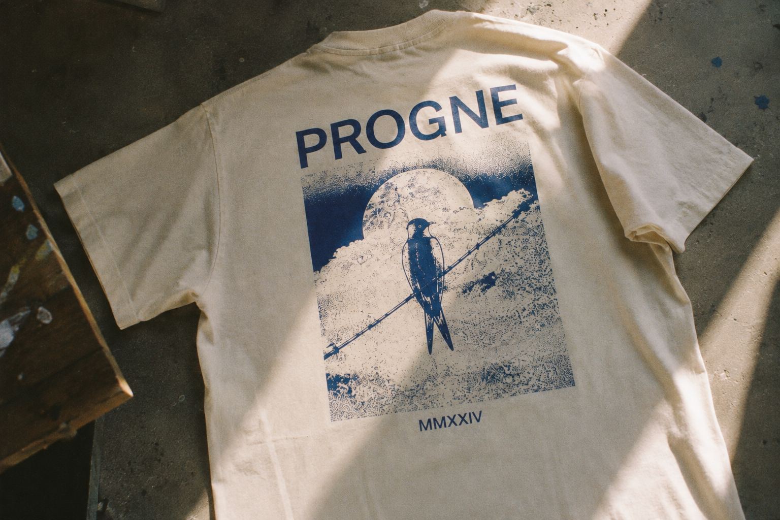 Numbered art-edition tee with a swallow-on-a-wire print